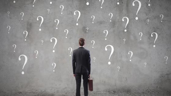 Image of business man facing question marks