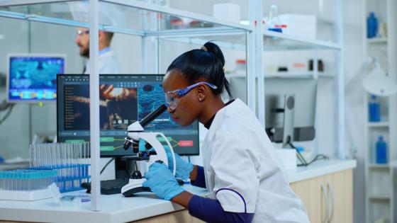 Scientist checking sample of virus using microscope in modern lab.