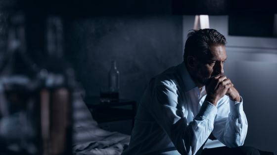 Man sitting on bed appearing depressed