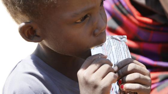 Child eats a sachet of therapeutic food at a health clinic in Turkana County, Kenya