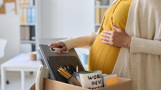 Pregnant woman packing her things in box before going on parental leave