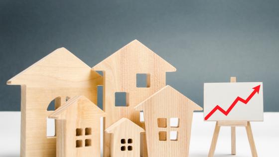 Wooden toy houses next to upward pointing chart