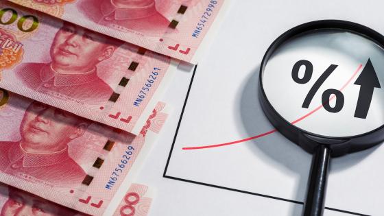 Chinese currency and magnifying glass over percent symbol
