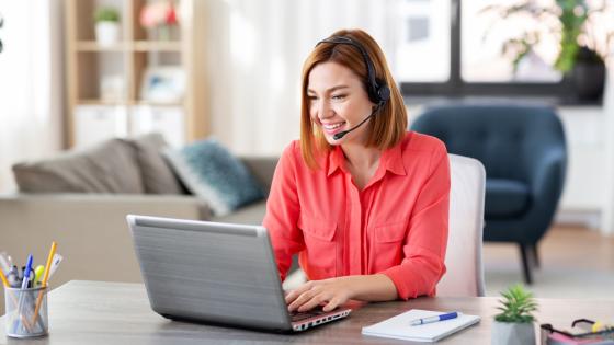 Woman working on laptop and using headset at home